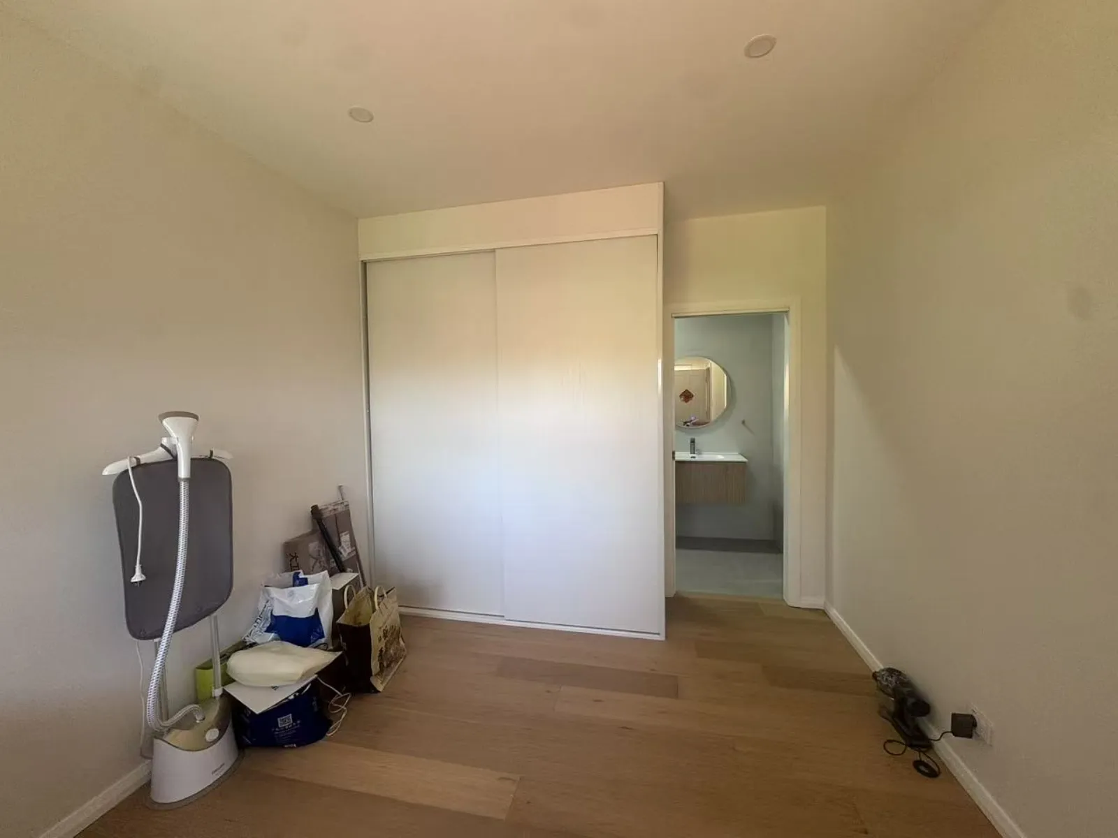 Completed Turramurra bedroom with timber flooring, white sliding wardrobe and adjoining bathroom